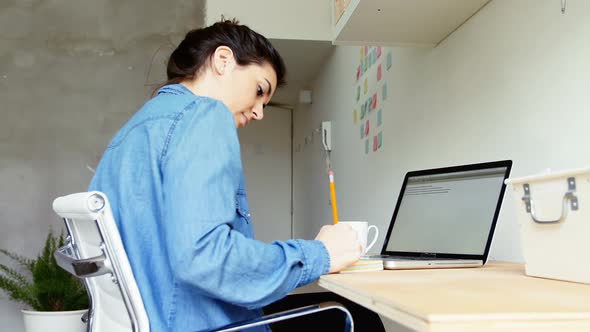 Female executive writing on sticky notes at desk