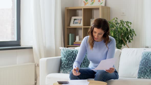 Woman with Papers and Calculator at Home