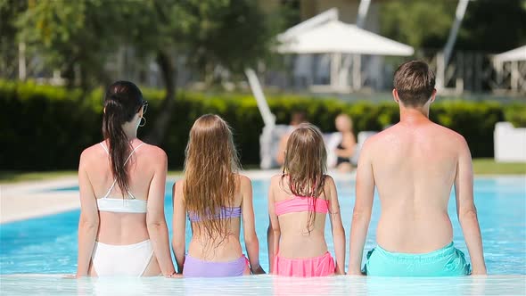 Happy Family of Four in Outdoors Swimming Pool