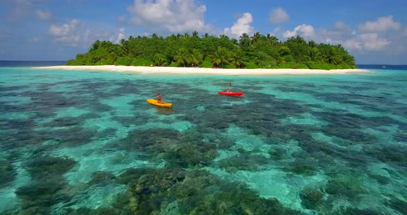 Aerial drone view of a man and woman couple kayaking around a tropical island