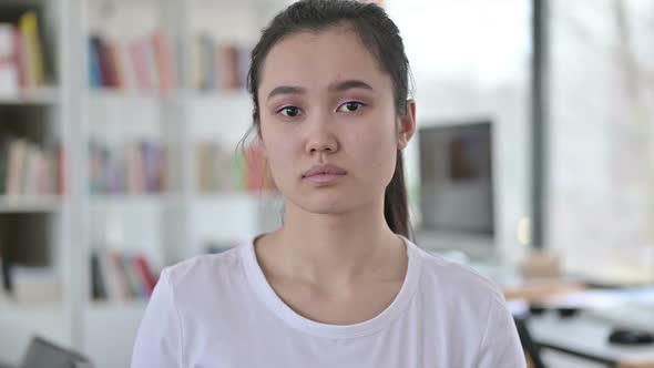 Portrait of Serious Young Asian Woman Looking at Camera