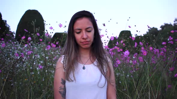 young latin woman sad and thinking deeply in the middle of a beautiful purple field with tinny flowe