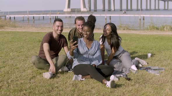 Smiling Friends Looking at Smartphone While Posing for Selfie