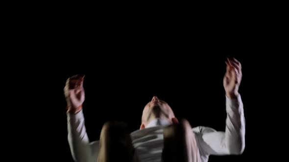 Male Gymnast in White Clothes on a Black Background Jumping on a Trampoline in Slow Motion