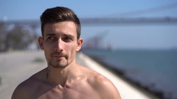 Handsome Muscular Tattooed Man Jogging Along Embankment