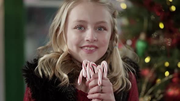 Young girl smiling as she turns holding candy canes