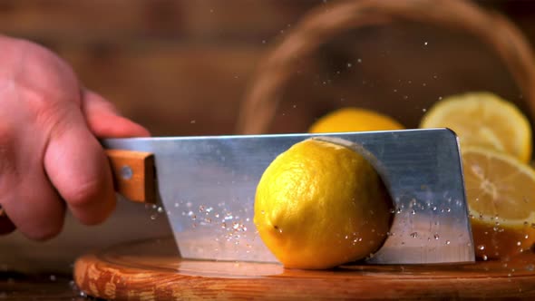 Super Slow Motion the Male Hand with a Knife Cuts the Lemon Into Two Halves