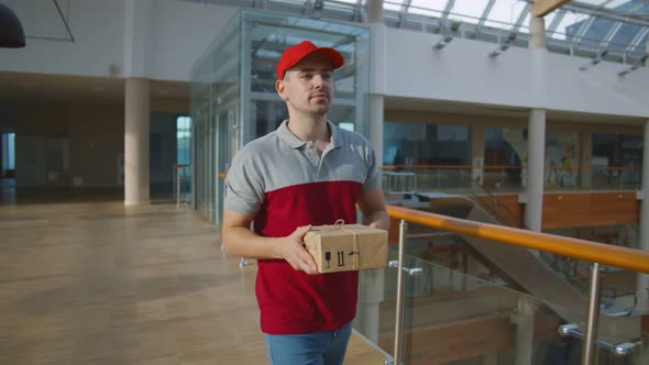 Postman Carrying Parcel Box To Deliver To Customer in Business Center