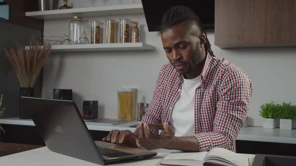 Handsome African American Man with Dreadlocks Making Online Shopping with Credit Card Indoors