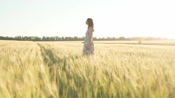 Girl in a Dress in a Wheat Field at Sunset