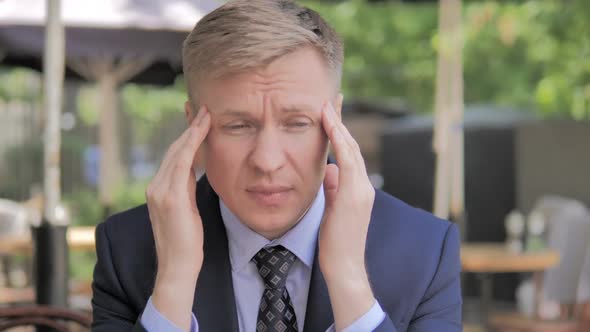 Headache Tense Businessman Sitting in Outdoor Cafe