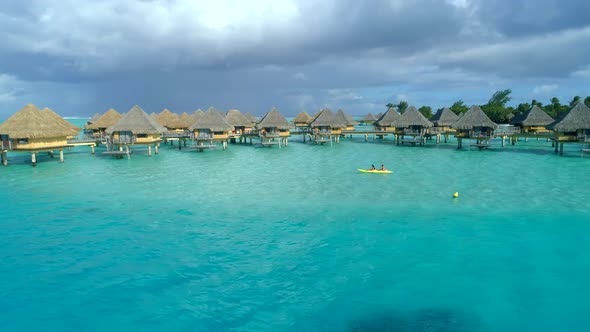 Aerial drone view of a man and woman couple on a tandem sea kayak in Bora Bora tropical island.