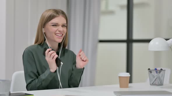 Young Woman Listening to Music on Smartphone at Work