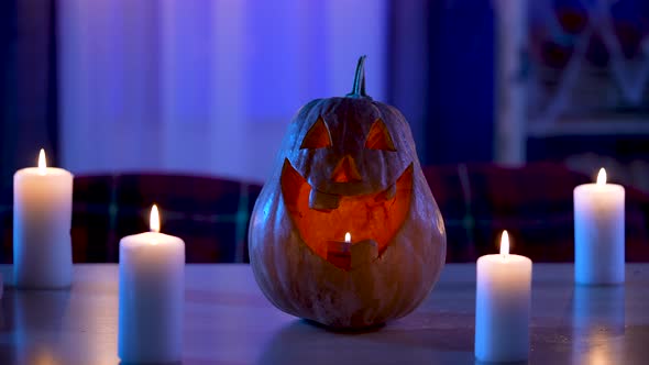 Traditional Halloween Pumpkin with Carved Smiling Face Glows on the Table in the Dark