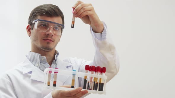 The Doctor Wearing Special Laboratory Glasses Examines Test Tubes with Blood