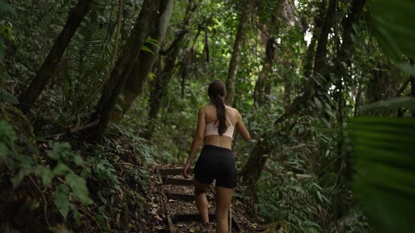 Young Fit Girl Hiking Through Jungle with Stick Slow Motion