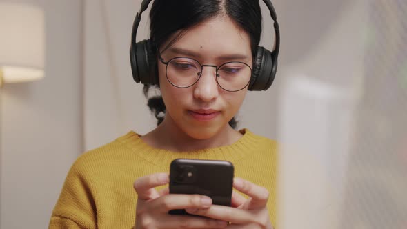 Young woman typing message on mobile and listening to music.