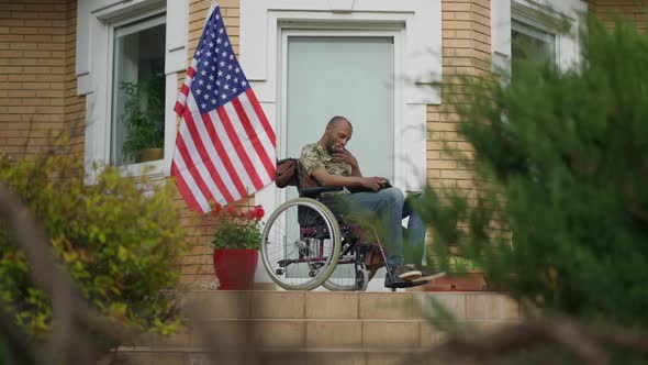 Disabled African American Military Man in Wheelchair Looking Through Pictures Smoking Cigarette on