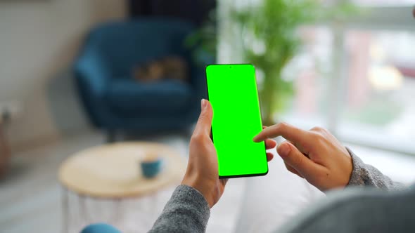 Woman at Home Using Smartphone with Green Mockup Screen in Vertical Mode