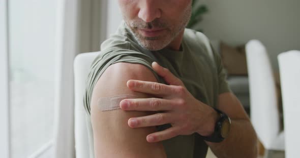 Portrait of caucasian man with vaccinated shoulder at home