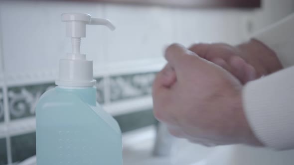 Close-up of Man Disinfecting Hands with Hand Sanitizer. Male Palms Applying Liquid in Bathroom