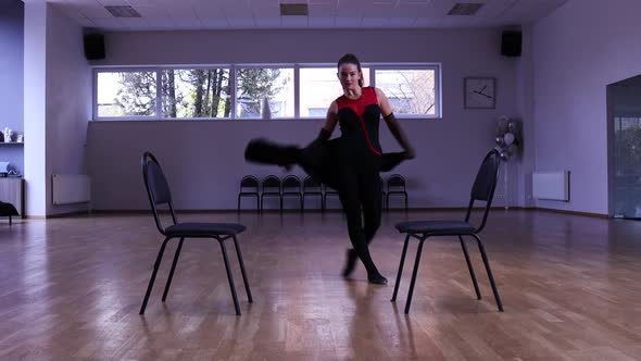 Professional female dancer dances around two chairs