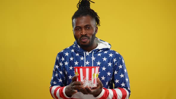 Confident Joyful African American Man Eating Popcorn Looking at Camera Posing at Yellow Background