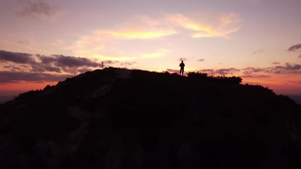 Person Standing on Rock with Epic Mountain Viewpoint with a Sunset Drone Aerial Landscape Shot