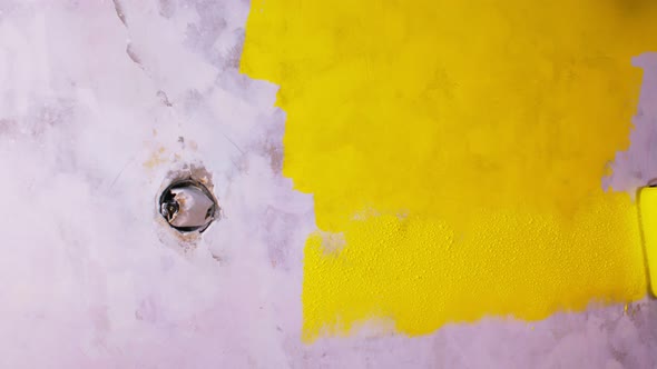 Close Up of Woman's Hand in Protective Glove Painting Wall in Yellow Colour with Roller