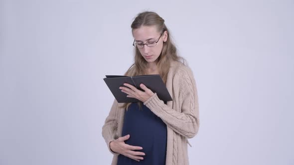 Young Pregnant Woman Reading Book with Eyeglasses