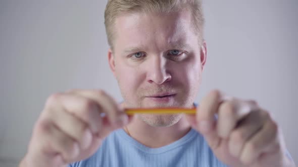 Close-up of Angry Caucasian Man with Grey Eyes and Red Hair Breaking Pencil. Portrait of Stressed