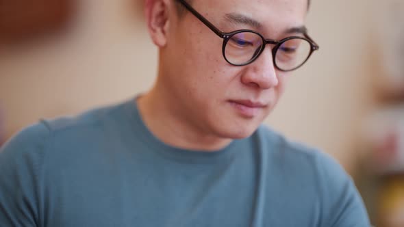 Concentrated Asian young man wearing eyeglasses working