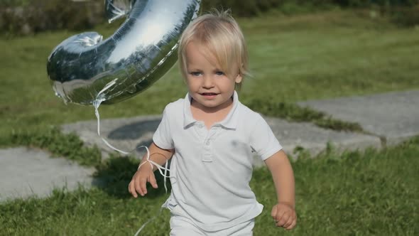 Attractive Little Boy in White Clothes Runs on the Grass in Sunny Weather