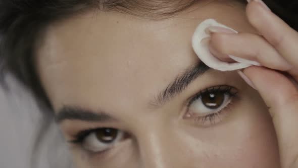 Beauty Close-up of Girl Cleansing Eyebrow Zone with Cotton Pad