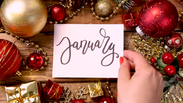 Hands bringing Christmas card with text JANUARY close to camera