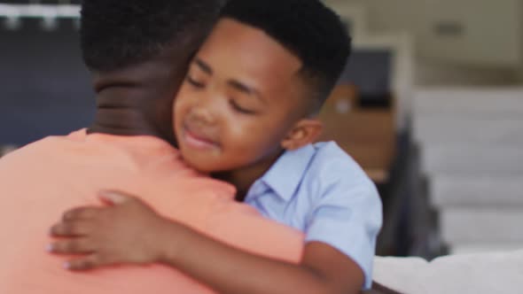 African american father and son embracing on a couch