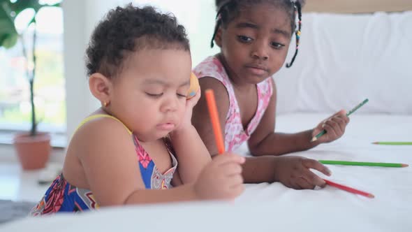 African American little girls play together near bed with one play pencil