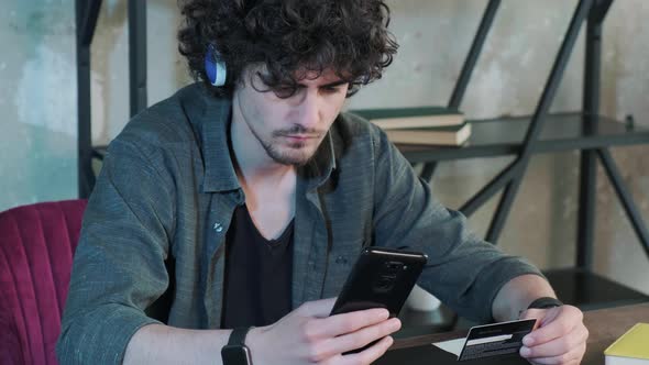 Young Man Shopping Online with Credit Card Using Smart Phone at Home