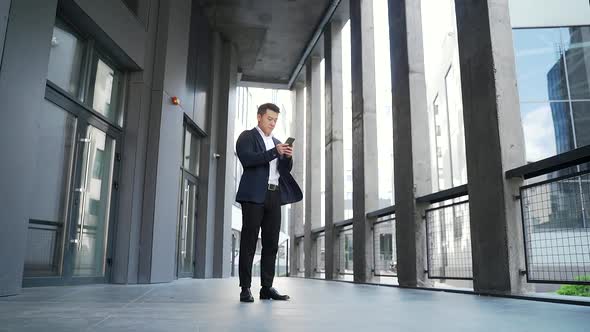 successful young confident businessman with cellphone in hands background of modern 