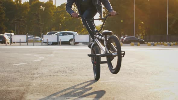 Skillful Teenager in Casual Outfit is Riding Bmx Bicycle and Performing Difficult Tricks While