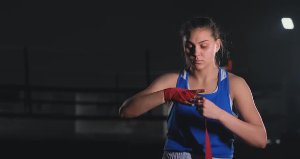 Woman Fighter Preparing for Battle Winds Up Hands in Boxing Bandages