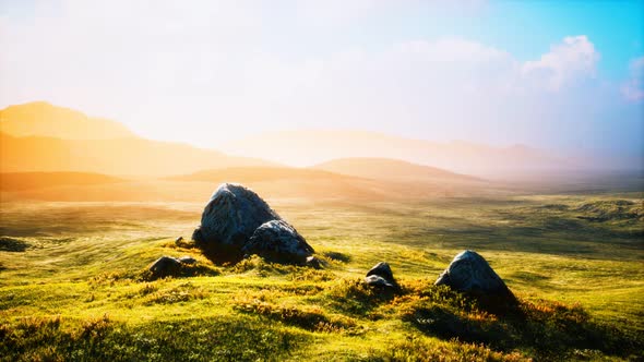 Meadow with Huge Stones Among the Grass on the Hillside at Sunset