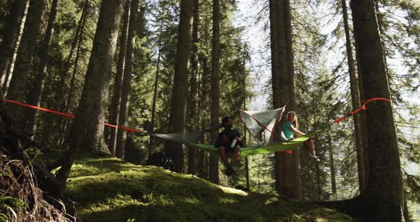 People Hanging Tent Camping in Forest Near Lake with Sun Flares Sunlight