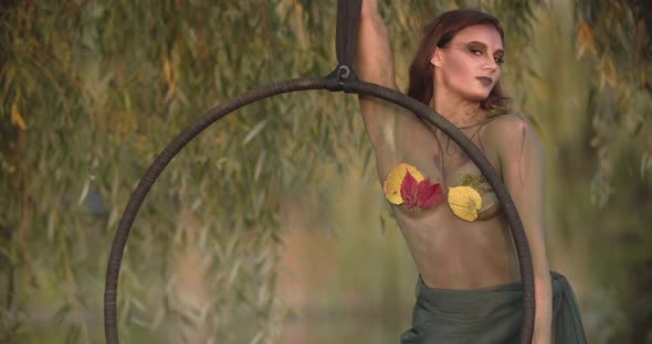 Elegant Young Woman with Body Art and Makeup of a Dryad is Posing with a Hoop