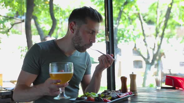 Man Eating Meat And Drinking Beer At Grill Restaurant