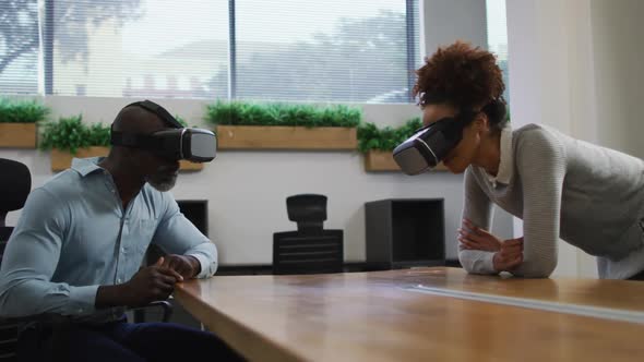 Diverse male and female business colleagues wearing vr headsets in office
