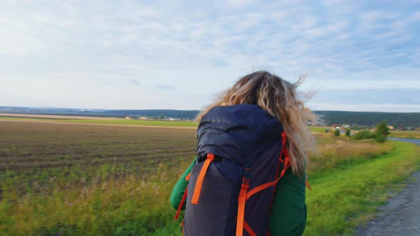 Girl Traveller with Backpack is Walking on Road