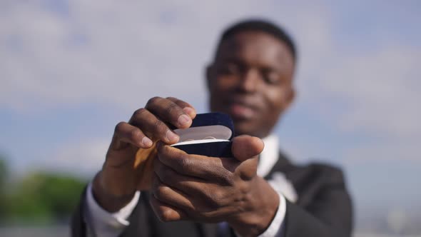 Closeup African American Male Hands Opening Box with Wedding Rings