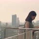 Woman using tablet chatting with friends while standing beside a balcony on a rooftop. - VideoHive Item for Sale
