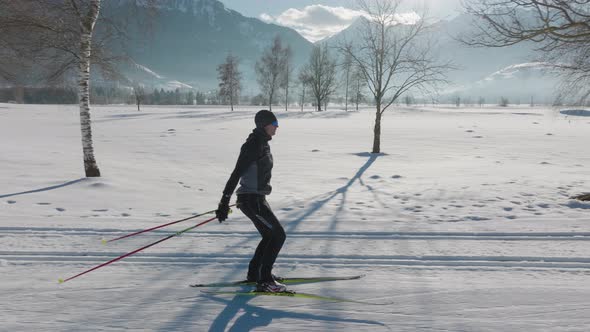 Cross Country Skier Skiing Along Snowy Path Under Sun